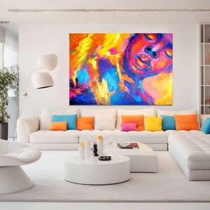 May include: A modern living room with a large abstract painting in vibrant colors of yellow, orange, blue, and pink. A white sectional sofa with colorful throw pillows and a white chair complete the contemporary design.