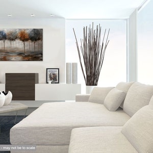 May include: A white sectional sofa with multiple pillows in a modern living room. The sofa is in front of a large window with white curtains. A painting of trees in shades of blue, brown, and gray hangs on the wall above a brown entertainment center.
