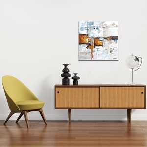 May include: A mid-century modern living room with a yellow chair, a wooden sideboard, and a black and white abstract painting on the wall. The sideboard has two doors and a drawer. There are three black ceramic vases on top of the sideboard.