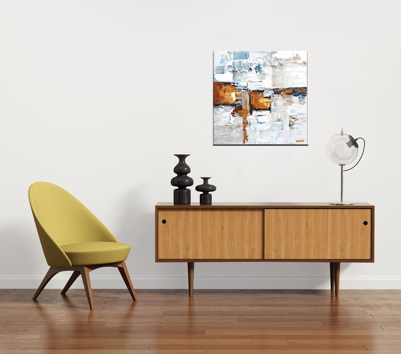 May include: A mid-century modern living room with a yellow chair, a wooden sideboard, and a black and white abstract painting on the wall. The sideboard has two doors and a drawer. There are three black ceramic vases on top of the sideboard.
