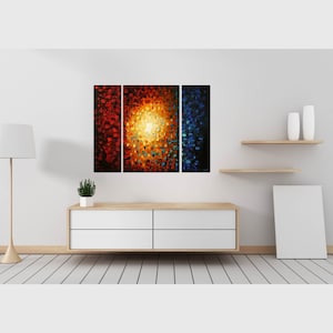 May include: A three-piece abstract painting with a central panel featuring a bright yellow sunburst surrounded by red, orange, and blue hues. The side panels are red and blue.