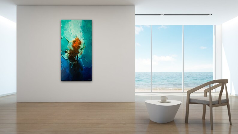 May include: Abstract painting with blue, green, and orange colors. The painting is hanging on a white wall in a modern living room with a view of the ocean.