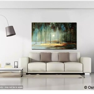 May include: A white couch with gray pillows in front of a painting of a forest scene with a bright white sun shining through the trees. The painting is on a white wall with a floor lamp and a coffee table with a vase and books on it. A green plant is in a pot on the right side of the image.