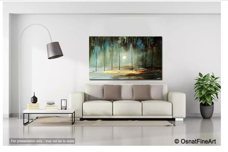 May include: A white couch with gray pillows in front of a painting of a forest scene with a bright white sun shining through the trees. The painting is on a white wall with a floor lamp and a coffee table with a vase and books on it. A green plant is in a pot on the right side of the image.