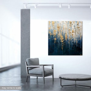 May include: Abstract textured painting with gold and deep blue tones. The artwork is displayed on a white wall in a modern interior setting. A gray armchair and a round coffee table are in the foreground.