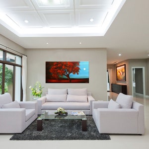 May include: A living room interior with white couches and a coffee table. A large painting of a red tree with a full moon in the background hangs on the wall.