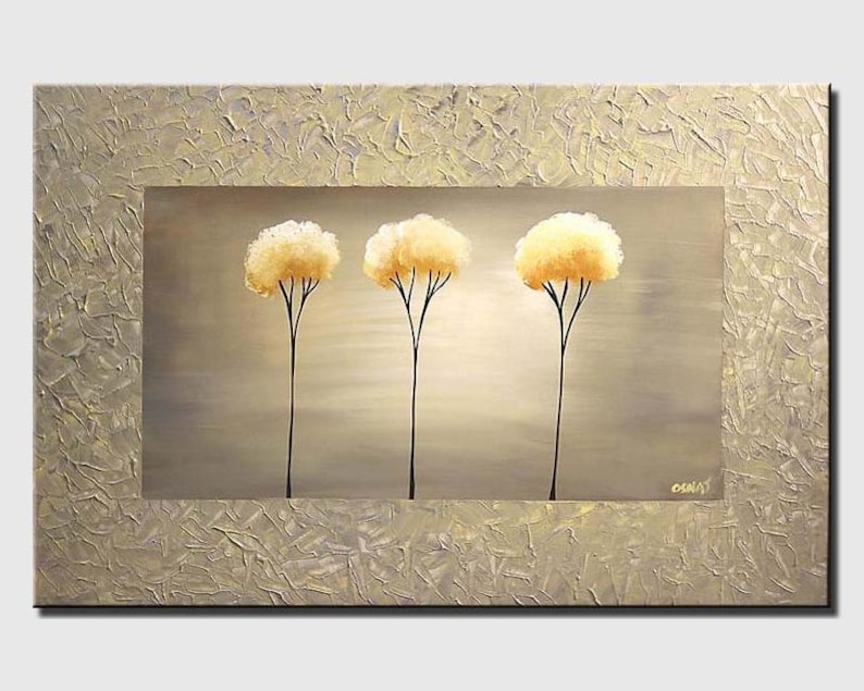 May include: A painting of three stylized trees with yellow foliage against a light gray background. The trees are painted in a minimalist style with simple black trunks and branches. The painting is framed with a textured gold border.