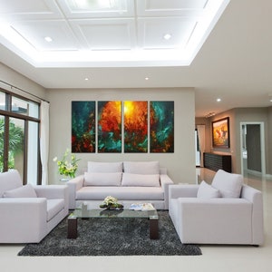 May include: A living room interior with a white sofa and two armchairs, a glass coffee table, and a large abstract painting on the wall. The painting is made up of four panels, each with a different color and design. The room has a modern and minimalist design.