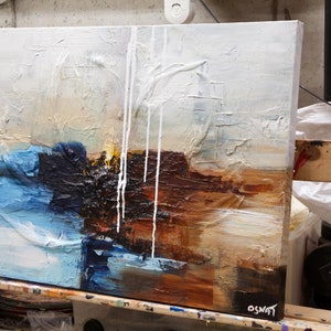 May include: Abstract painting on canvas with white, blue, brown, and black paint. The paint is applied in thick layers and has a textured surface. The painting is signed "OSNAT" in the lower right corner.
