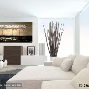 May include: A painting of a row of trees with white clouds as canopies, set against a beige background. The trees are silhouetted against a dark blue sky. The painting is displayed on a white wall in a modern living room setting.