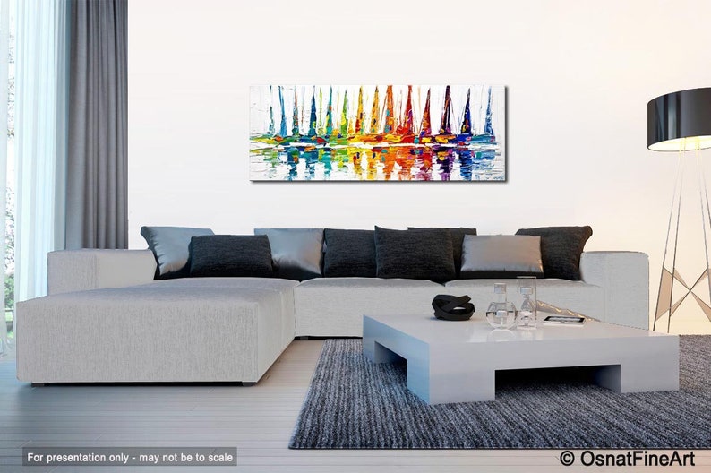 May include: Abstract painting of colorful sailboats on a white background with reflections in the water. The painting is displayed on a wall in a living room setting.