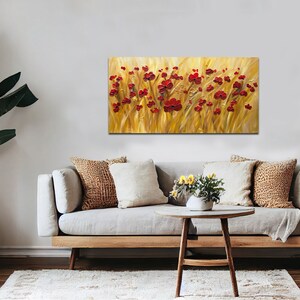 May include: A painting of a field of red poppies against a golden background. The painting is framed and hanging on a wall above a couch.