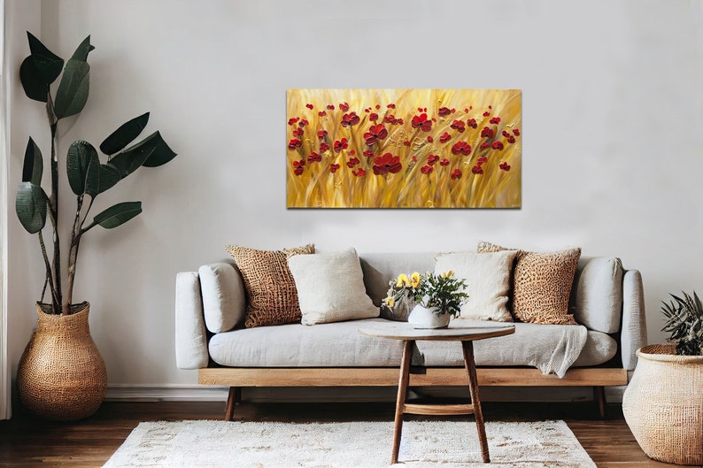 May include: A painting of a field of red poppies against a golden background. The painting is framed and hanging on a wall above a couch.