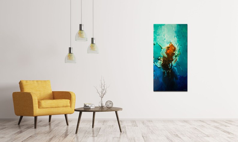 May include: Abstract painting with blue, green, and orange colors. The painting is hanging on a white wall in a living room setting with a yellow armchair and a coffee table.