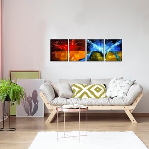 May include: A set of four abstract art prints featuring a mix of red, orange, yellow, and blue colors. The prints are arranged in a row on a white wall above a light-colored couch.