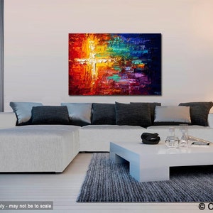 May include: Abstract painting with a white cross shape in the center, surrounded by vibrant colors like red, orange, yellow, green, blue, and purple. The painting is displayed on a white wall above a white sectional sofa with gray pillows and a white coffee table.
