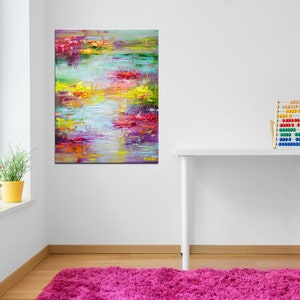 May include: Abstract painting with vibrant colors of yellow, red, pink, blue, and green. The painting depicts a landscape with water and flowers. The painting is framed and hanging on a white wall.