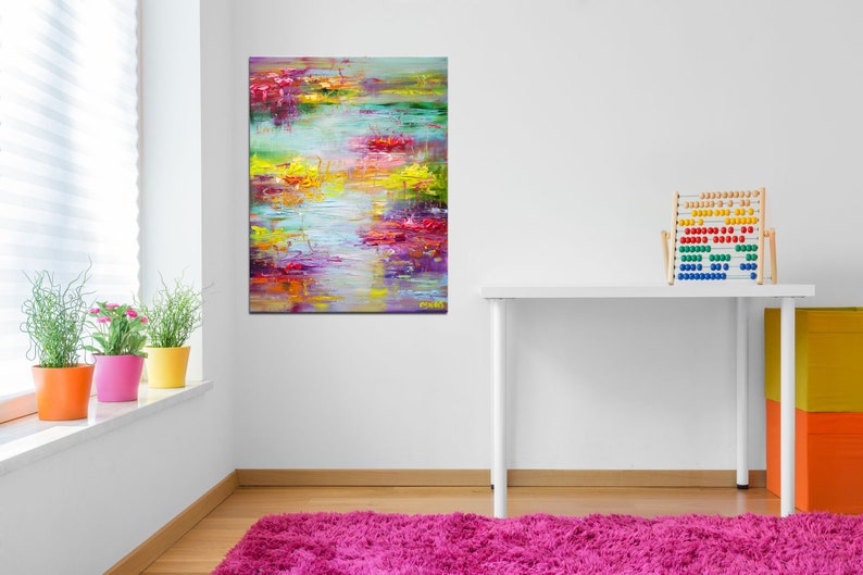 May include: Abstract painting with vibrant colors of yellow, red, pink, blue, and green. The painting depicts a landscape with water and flowers. The painting is framed and hanging on a white wall.