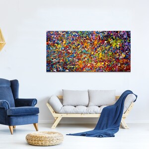May include: Abstract painting with a colorful, textured, and layered design. The painting features a variety of colors, including red, orange, yellow, green, blue, and purple. The painting is displayed on a white wall in a living room setting.