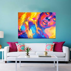 May include: Abstract art canvas print featuring a vibrant portrait with a face in shades of red, purple, yellow, and blue. The artwork is displayed above a white sofa with colorful throw pillows, creating a modern living room setting.