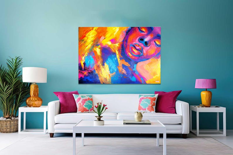 May include: Abstract art canvas print featuring a vibrant portrait with a face in shades of red, purple, yellow, and blue. The artwork is displayed above a white sofa with colorful throw pillows, creating a modern living room setting.