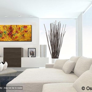 May include: Abstract painting with a yellow background and red, green, and blue accents. The painting is displayed in a modern living room with a white couch and a vase of brown branches.