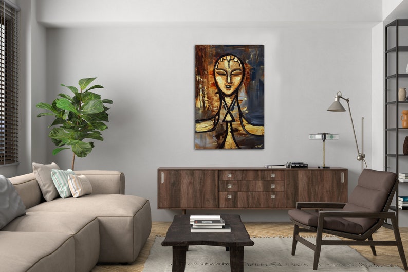 May include: Abstract painting of a person's face with a gold and brown background. The painting is framed and hanging on a wall in a living room.