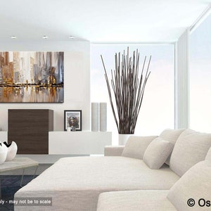May include: Abstract cityscape painting with gold, brown, and gray tones. The painting is hanging on a white wall in a modern living room with a white couch and a vase of brown branches.