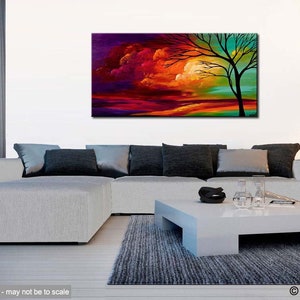 May include: Abstract painting of a tree with a colorful sunset sky in the background. The painting is displayed on a white wall above a white couch with gray pillows.