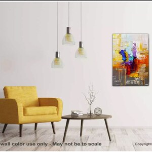 May include: Abstract painting with bold strokes of yellow, orange, red, blue, purple, and gray. The painting is hanging on a white wall in a living room setting with a yellow armchair and a coffee table.