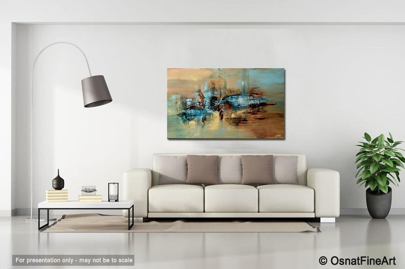 May include: Abstract painting with blue, brown, and gold hues. The painting is hanging on a white wall above a white couch with brown pillows.
