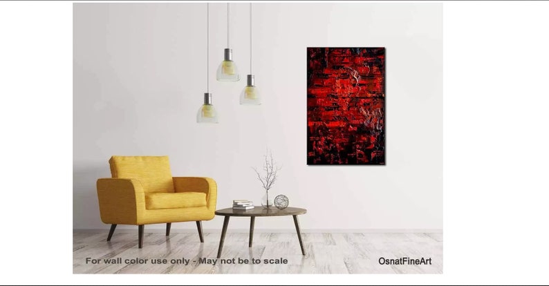 May include: Abstract painting with red, black, and white paint. The painting is hanging on a white wall in a living room setting with a yellow armchair and a coffee table.