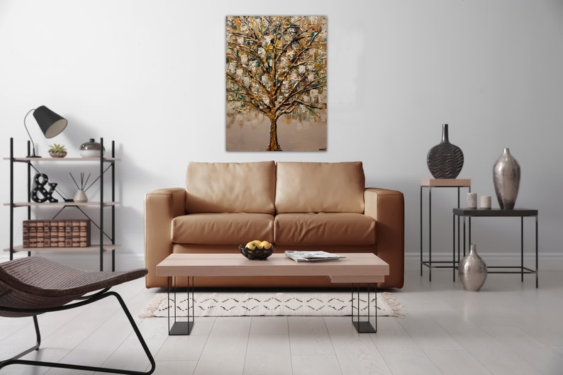 May include: A living room interior design with a brown leather sofa, a coffee table, a black metal shelf, and a painting of a gold tree on the wall.