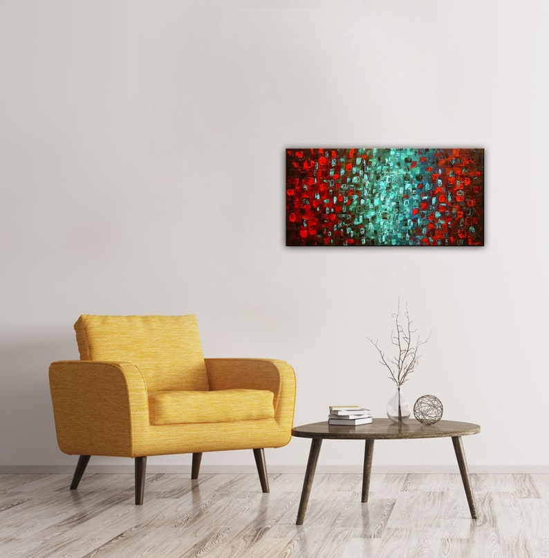 May include: Abstract painting with a red and teal color scheme. The painting is made up of small squares of color, creating a textured effect. The painting is hanging on a white wall above a yellow armchair and a coffee table.