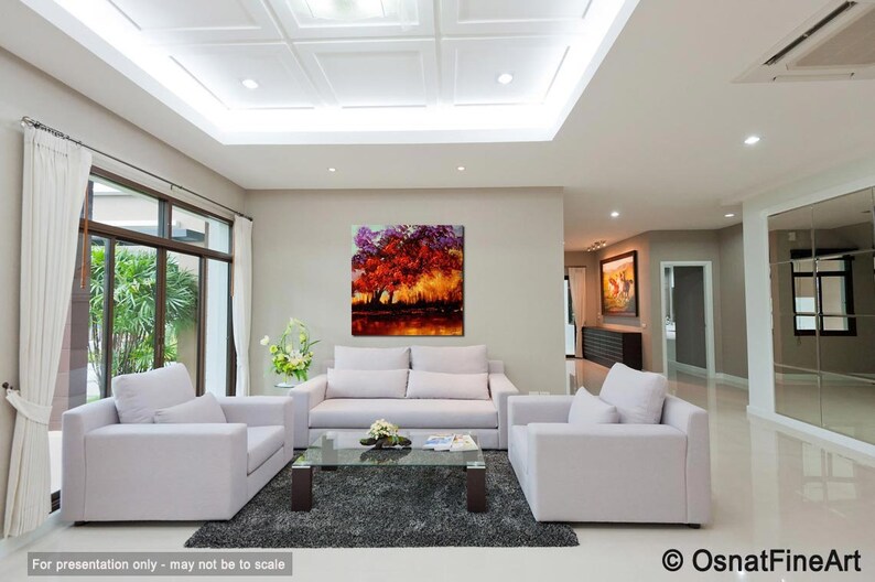 May include: A living room interior with white furniture, a large painting of a colorful tree, and a glass coffee table. The painting is a vibrant mix of red, orange, yellow, and purple.
