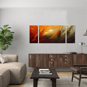 May include: Abstract art print in three panels, featuring a sunset scene with orange, yellow, and brown hues. The panels are hung on a white wall above a brown wooden cabinet.
