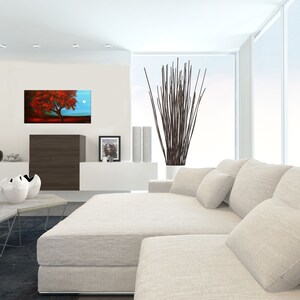 May include: A white sectional sofa with multiple pillows in a modern living room. A painting of a red tree with a full moon in the background hangs on the wall above a dark brown cabinet.