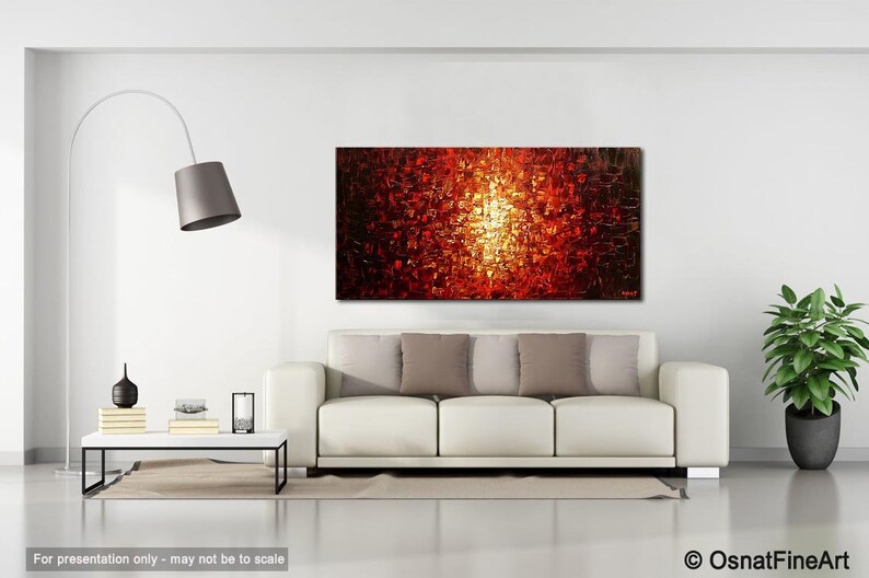 May include: Abstract painting with a bright orange, yellow, and red color scheme. The painting is displayed on a white wall above a white couch with pillows.