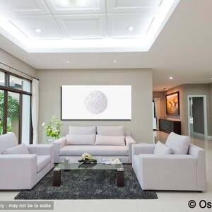 May include: A white living room with two white sofas, a coffee table, and a large white framed canvas with a white circle design. The room has a high ceiling with recessed lighting and white curtains.