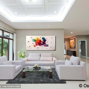 May include: A colorful abstract painting of flowers in shades of pink, red, orange, yellow, blue, and green. The painting is on a white canvas and is framed in a white frame. The painting is hanging on a wall in a living room with white couches and a coffee table.