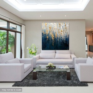 May include: An abstract painting with a textured surface, featuring a blend of deep blue and gold tones. The artwork is displayed above a white sofa in a modern living room setting. The room includes white armchairs, a glass coffee table, and a gray rug.