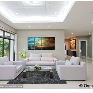 May include: A living room interior design featuring a multi-panel abstract painting with blue, green, orange, and brown hues. The painting is hung above a white sofa with two matching armchairs. The room has a modern aesthetic with a grey rug and a glass coffee table.