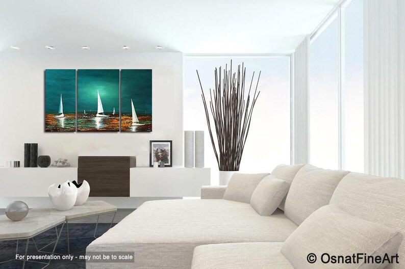 May include: A three-panel abstract painting of sailboats on a teal and turquoise ocean with a golden sunset. The painting is displayed in a modern living room with a white couch and a vase of brown branches.