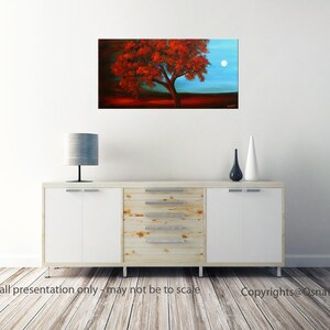 May include: A painting of a red tree with a full moon in the background. The tree is silhouetted against a blue sky. The painting is framed and hanging on a white wall.