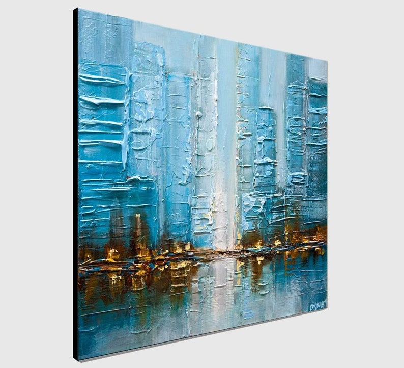 May include: Abstract painting of a city skyline in shades of blue, white, and gold. The painting has a textured surface and depicts a reflection of the city in the water.