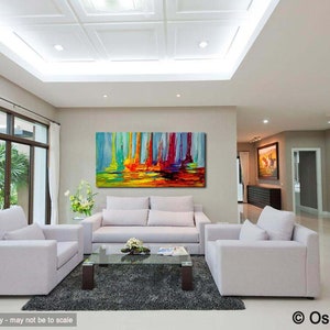 May include: Abstract painting of colorful vertical lines with a yellow, orange, and green base. The painting is hanging on a wall in a living room with white couches and a glass coffee table.