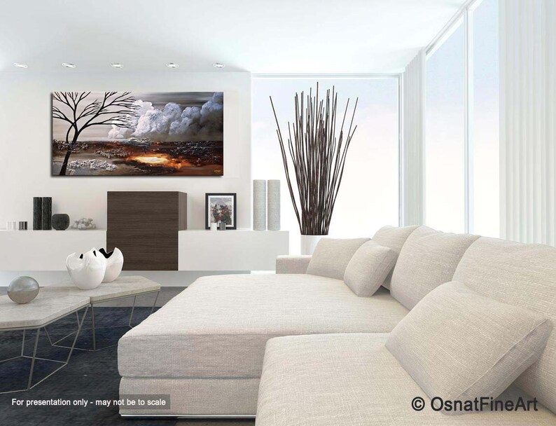 May include: Abstract painting of a tree with white clouds and a brown landscape. The painting is hanging on a white wall in a modern living room with a white couch and a coffee table.