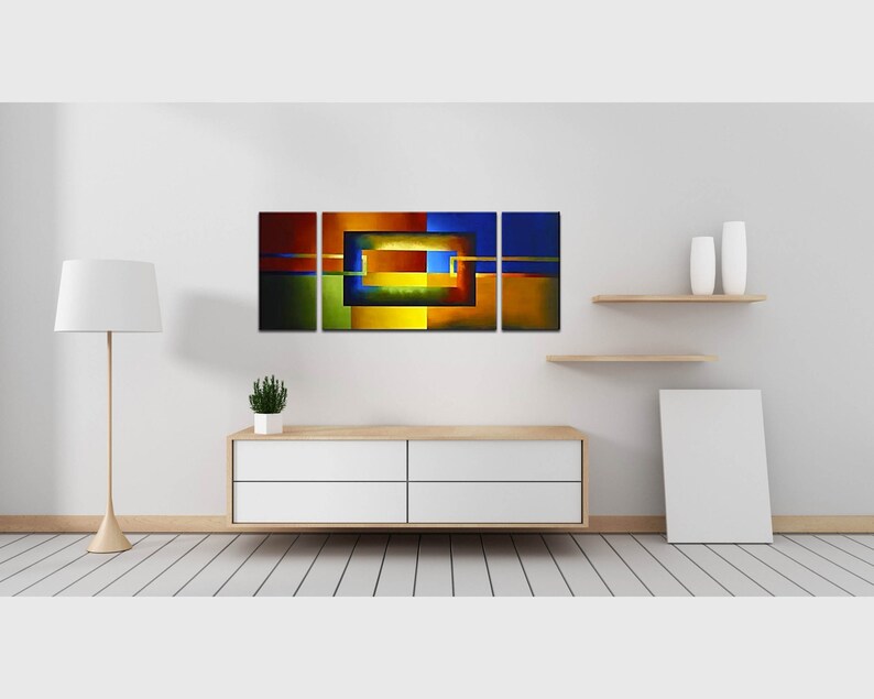 May include: Abstract art print with a geometric design in shades of blue, green, yellow, orange, and red. The print is divided into three panels and features a central square with a smaller square inside.