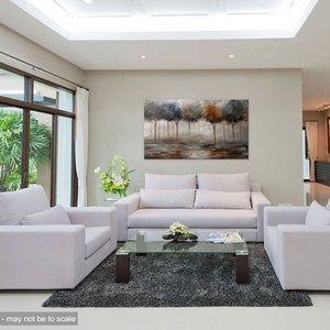 May include: A living room interior design featuring a large abstract painting of trees in shades of gray, brown, and white above a white sofa. Two white armchairs are placed on either side of the sofa, and a glass coffee table sits in front of the sofa. A gray rug covers the floor.
