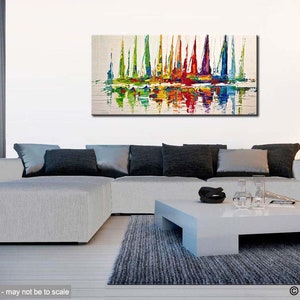 May include: Abstract painting of colorful sailboats on a white background. The sailboats are reflected in the water below. The painting is displayed on a wall in a living room setting.